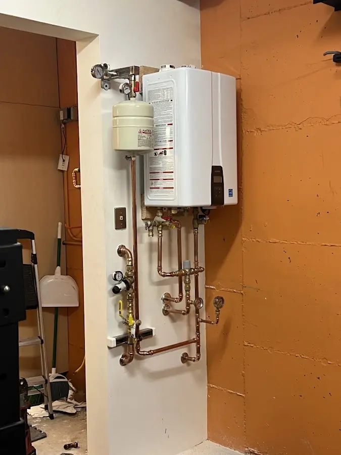 Plumbing technician inspecting water heater connections in Newfane